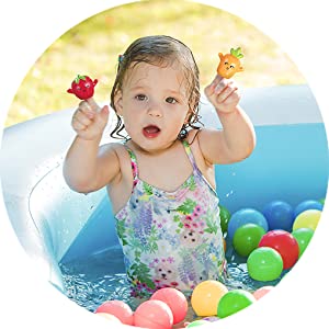 Niña jugando en piscina exterior con las marionetas de frutas y verdurasaeioubaby